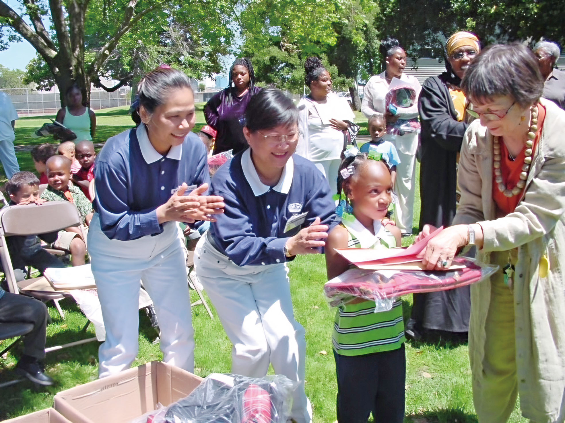 2002年5月30日，蘇素惠（左二）和林明珠（左一）參與屋崙的「啟蒙教育計畫」書包發放。
