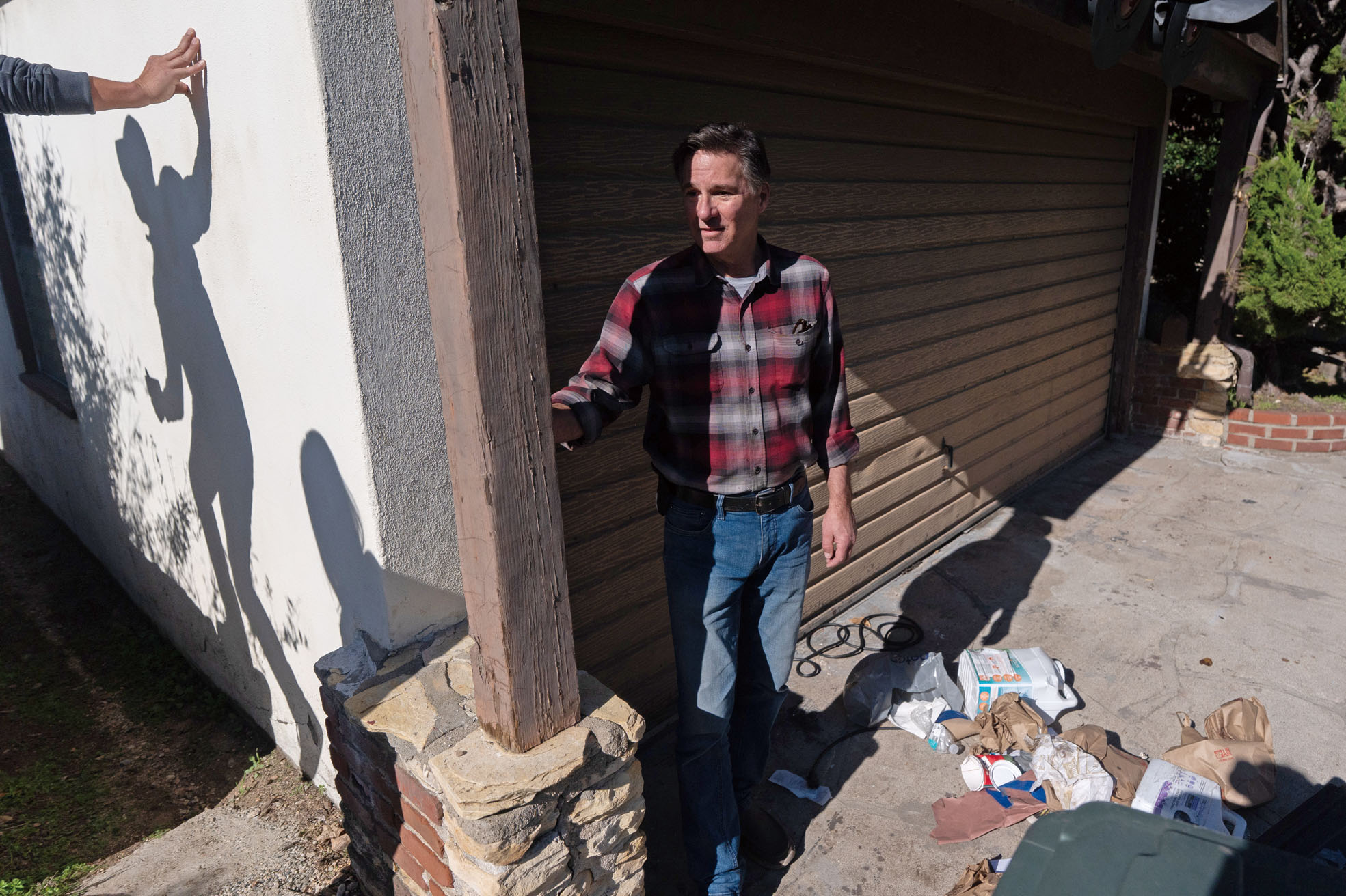 屋主約翰遜上月站在住所外受訪，車道上散落垃圾。圖中亦可見記者在現場查看情況，身影投射在牆上。美聯社