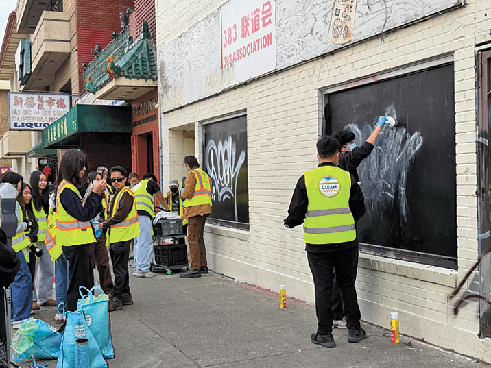 志願者使用清潔劑及刷具清除商戶牆面塗鴉，改善市容。記者蘇婕雅攝