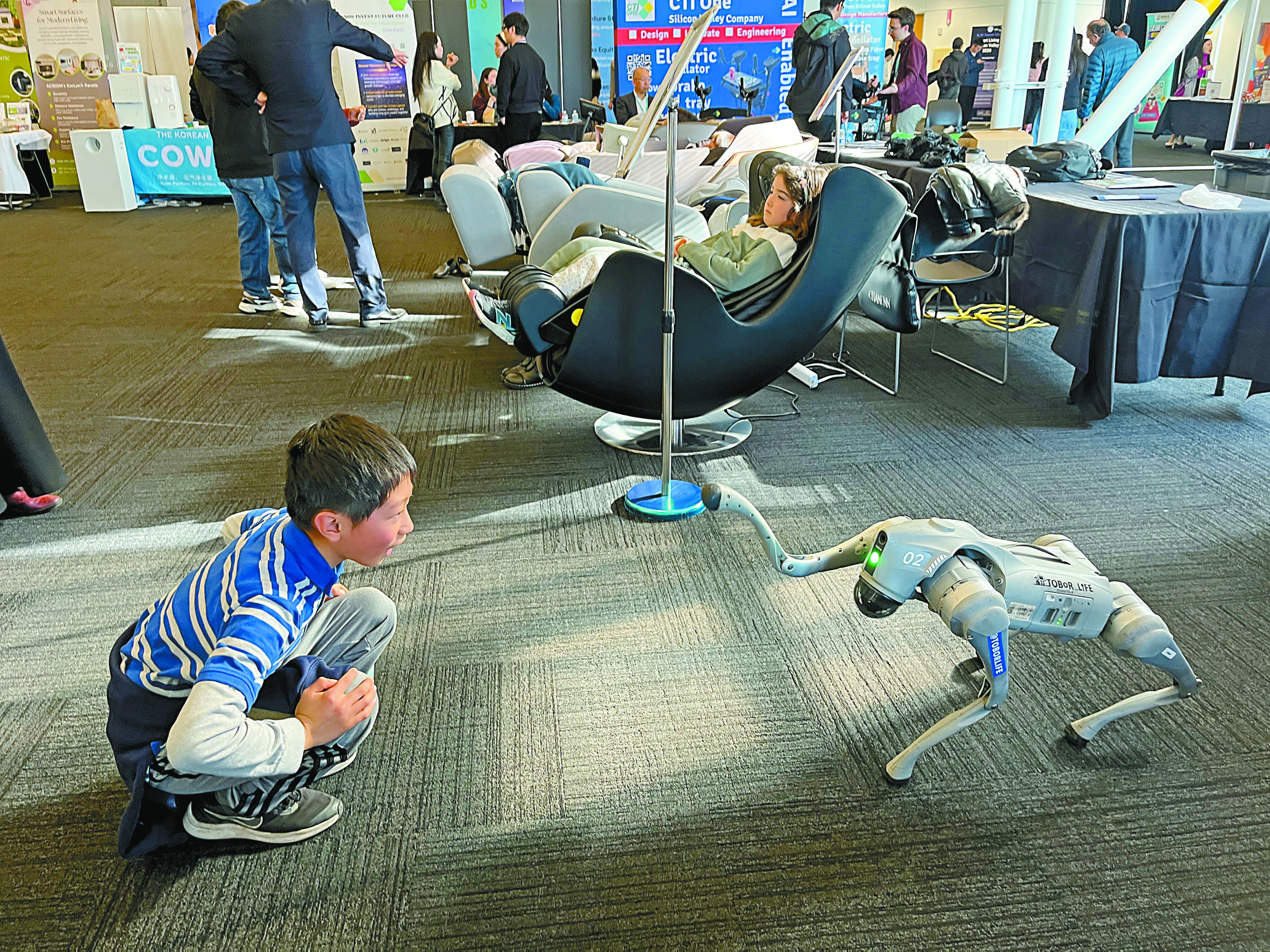 矽谷智生活高峰會展覽現場少年與機器狗互動。記者王蔚攝
