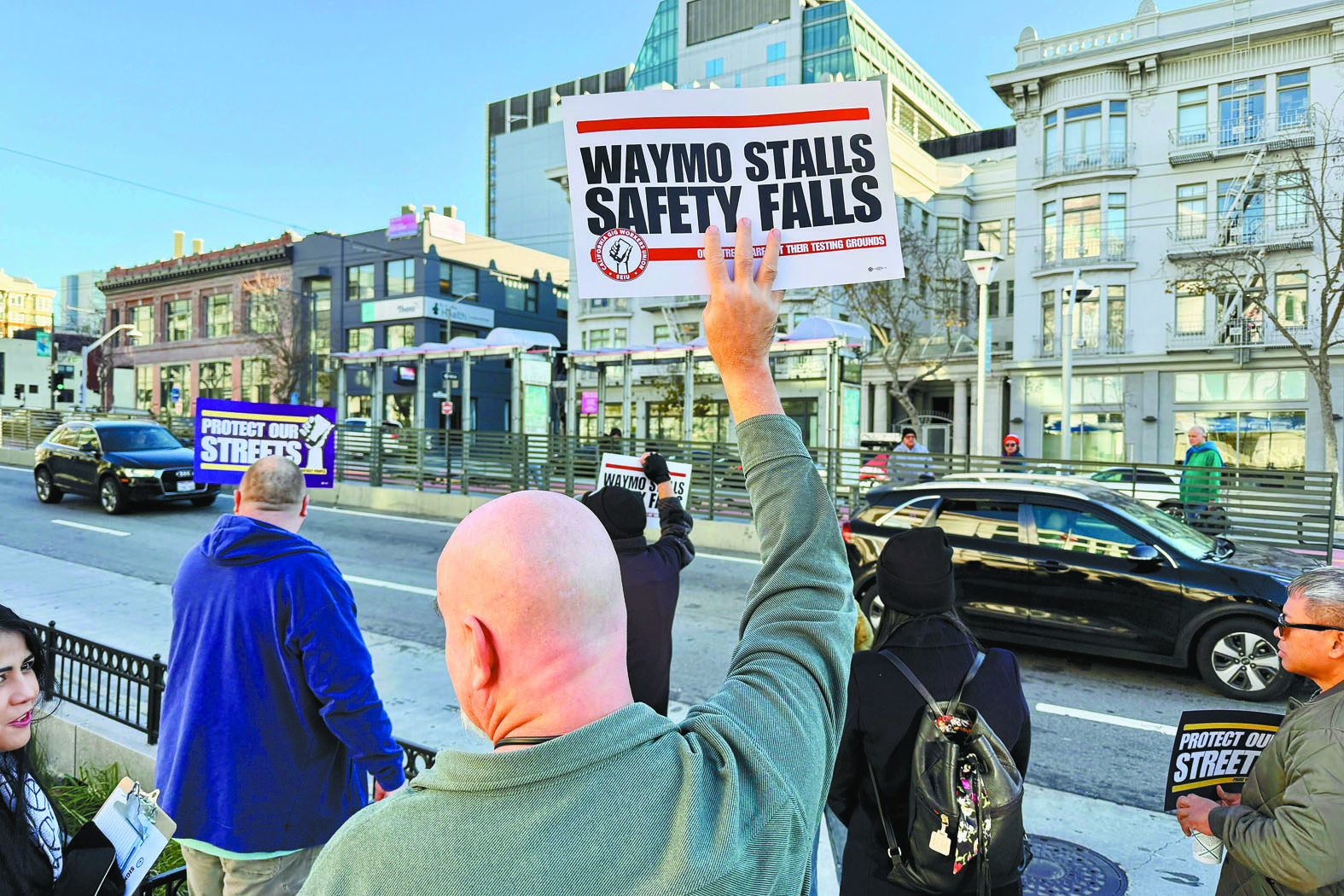 示威者9日在三藩市的加州共用事業委員會總部外舉牌抗議。美聯社