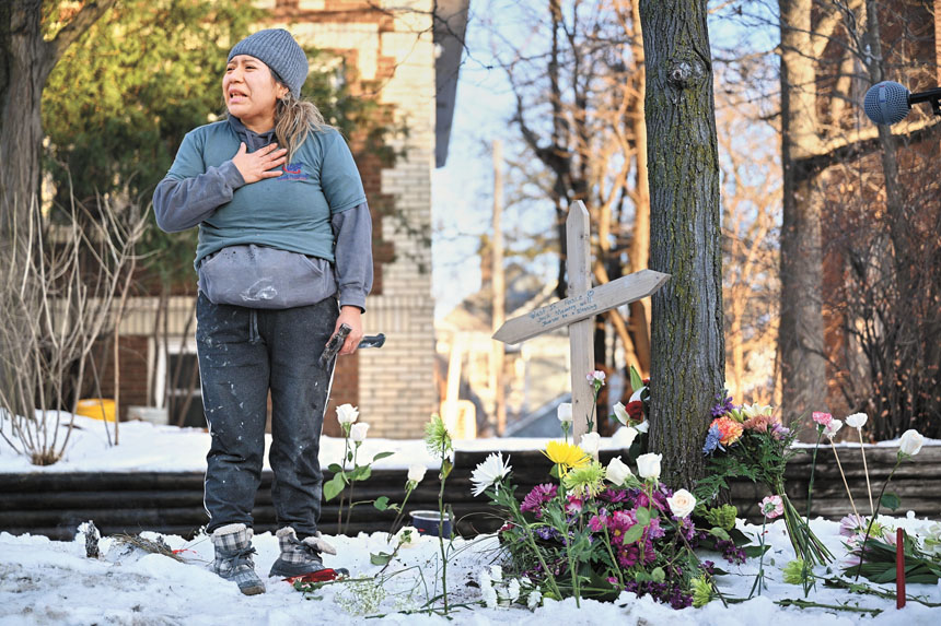 一名抗議者站在一個臨時搭建的紀念碑旁，悼念在聯邦執法人員槍擊事件中喪生的受害者。 美聯社
